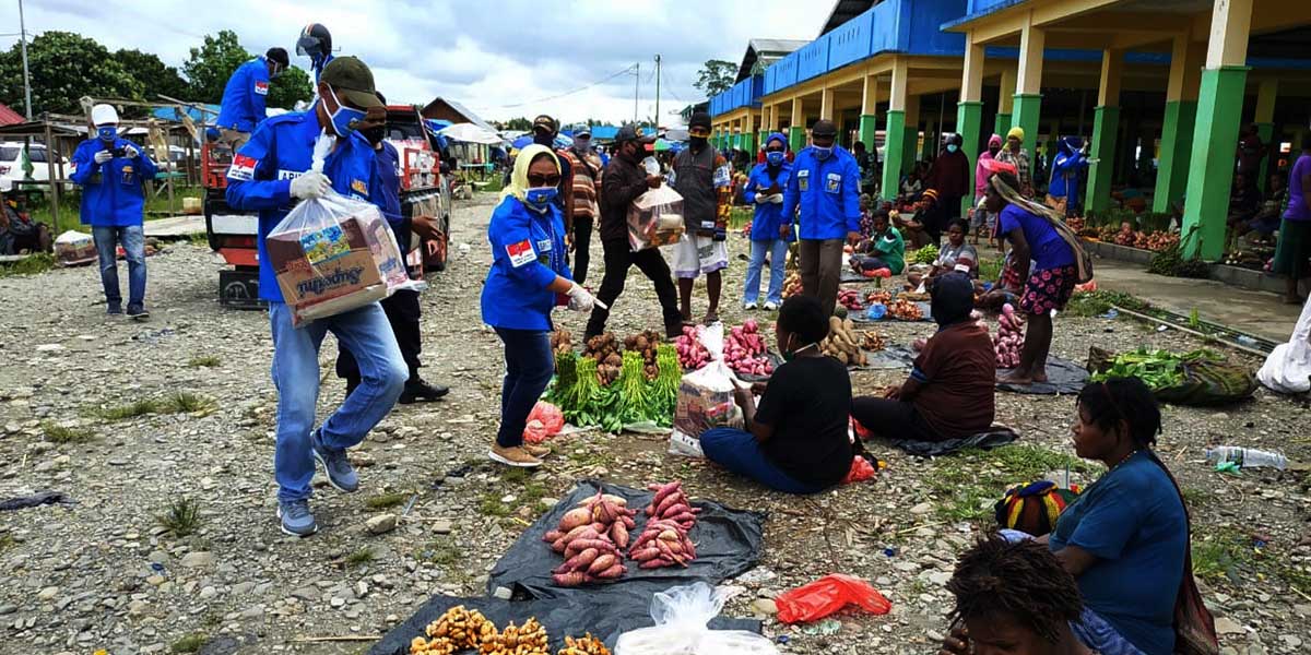 Pengurus KNPI dan relawan pemuda Mimika membagikan paket sembako kepada pedagang mama-mama Papua di Pasar Sentral Timika, Kamis (23/04/2020)